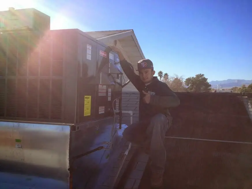 HVAC technician performing Heat Pump Repair on a rooftop unit in Springville